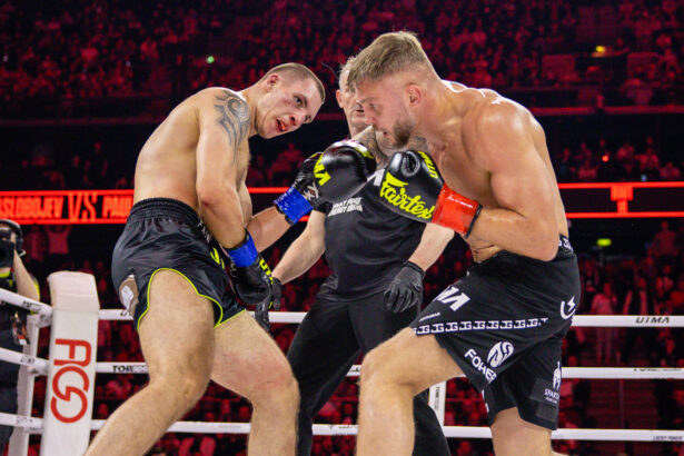 Two male boxers clash in the ring as they throw punches; a referee watches from behind them.
