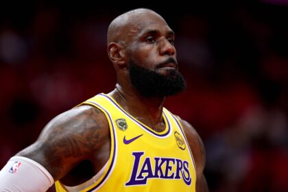 LeBron James wearing a yellow Los Angeles Lakers jersey, looking upwards with a focused expression.