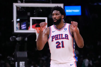 Philadelphia 76ers player wearing #21, fists raised in celebration on a basketball court during a game.