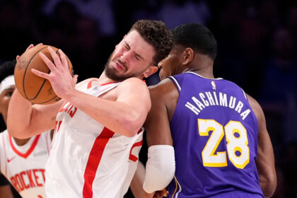 Two basketball players collide as they fight for the ball: one in a white uniform with red stripes, the other in a purple jersey number 28 (Hachimura).