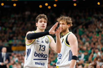 Two basketball players in white jerseys high-fiving on the court as a crowd watches in the background (player #13 visible).