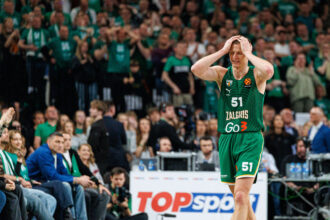 Basketball player in a green jersey with number 51 and 'Zalgiris' looks frustrated, hands on head, amid a cheering crowd.