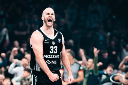 Basketball player wearing a black jersey #33 shouting on the court with a cheering crowd in the background
