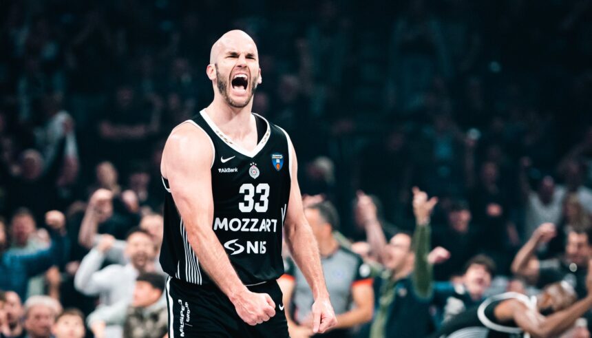 Basketball player wearing a black jersey #33 shouting on the court with a cheering crowd in the background