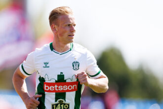 Male footballer in white and green kit (Zalgiris crest) sprinting on the field; bib number 1410 visible.