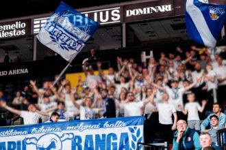 Crowd of sports fans in a stadium waving blue and white flags and banners.
