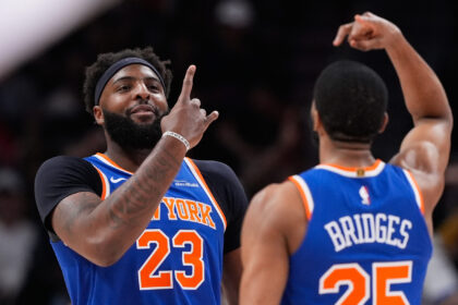 Two basketball players in blue New York Knicks jerseys celebrate on the court, one facing the camera wearing #23.