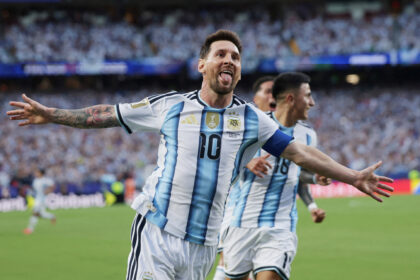 Argentinian soccer player celebrating with arms wide on the field in a blue-and-white striped jersey (number 10).