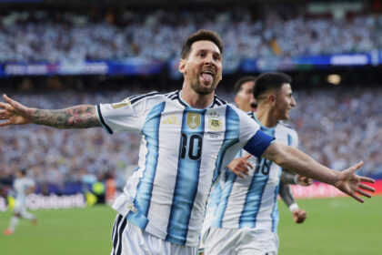 Argentinian soccer player celebrating with arms wide on the field in a blue-and-white striped jersey (number 10).