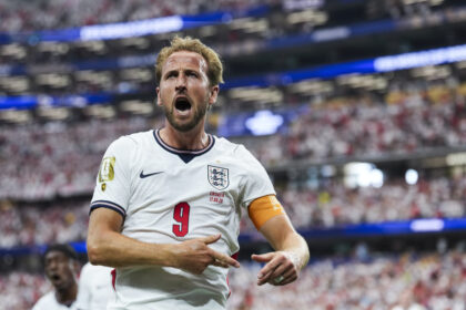 England forward in a white jersey with number 9, celebrating a goal amid a packed stadium crowd