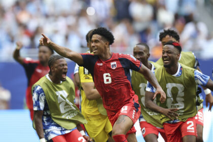 Group of soccer players in red kits celebrating on the field during a match.