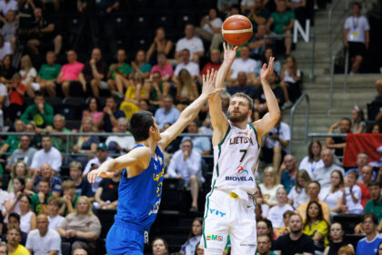 Basketball player in a white Lithuania jersey (number 7) rises to shoot while a blue-clad defender reaches in.