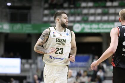 Basketball player in a white jersey number 23 runs on the court during a game, with a defender in a black jersey nearby.
