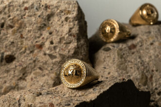Close-up of gold championship rings with diamond accents resting on rough stone surface.