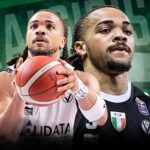 Two basketball players tightly framed, one in a white jersey and the other in a black jersey, reach for a basketball against a dark green geometric background with team logos nearby.