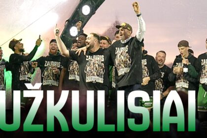 Group of athletes in matching 'Žalgiris Champions' shirts celebrate on stage, raising arms and cheering with bottles in hand.