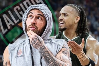 Two basketball players on the court celebrate: one in a gray hoodie looks thoughtful while the other, with braided hair, smiles excitedly nearby.