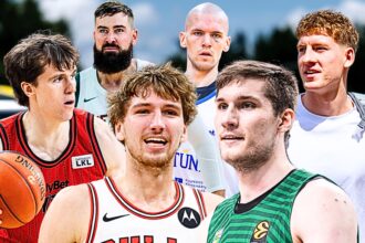 Six male basketball players pose together outdoors in colorful uniforms, one holding a basketball at the front.
