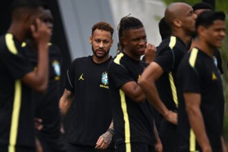 Group of Brazil national team players in black training kits with neon-yellow stripes, standing together during practice; central player looks forward.