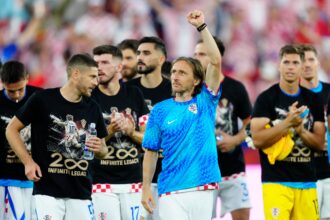 Group of Croatian athletes celebrate on the field; a player in a blue jersey raises his fist in the air amid teammates in black shirts.