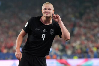 Soccer player in a black jersey with number 9 celebrating on the field, crowd in the background.