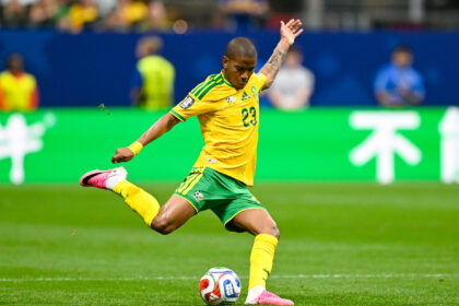 Brazil national team soccer player, number 23, in yellow kit kicking a ball on a green field during a match.