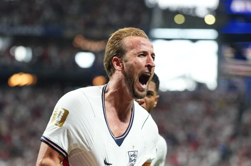 Footballer in England national team jersey celebrating on the pitch with mouth open in a roar of celebration.
