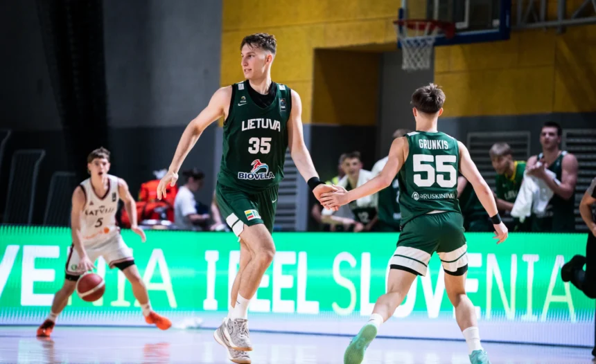 Lithuanian basketball player wearing number 35 in green jersey extends hand to teammate on a lit indoor court during a game.
