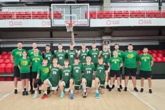 Lithuanian basketball team posing for a group photo on an indoor court, wearing green jerseys with 'LIETUVA'.
