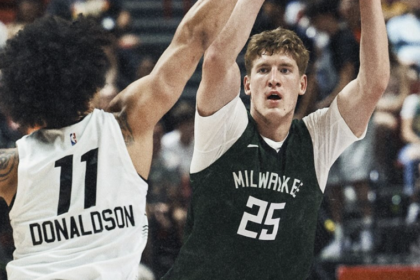 Two basketball players leap with arms raised as they guard each other during a game; one wears Milwaukee jersey #25, the other white #11 Donaldson in pursuit.