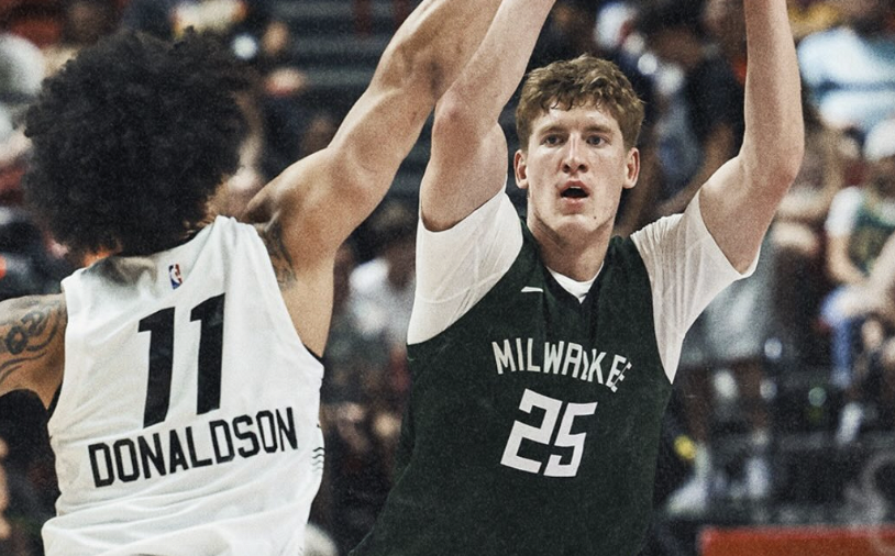 Two basketball players leap with arms raised as they guard each other during a game; one wears Milwaukee jersey #25, the other white #11 Donaldson in pursuit.