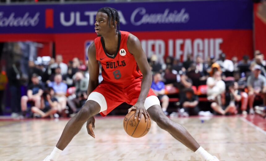 Basketball player in a red Bulls jersey dribbling the ball on a court with a crowd in the background
