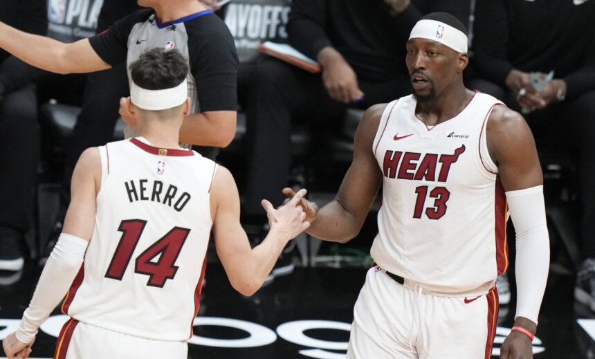 Miami Heat players high-fiving on a basketball court during a game; jersey numbers 14 and 13 visible, one with 'HERRO' on the back.
