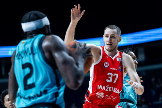 Basketball player in a red jersey (number 32) reaching up with his right arm during a high‑intensity moment against a blue defender.