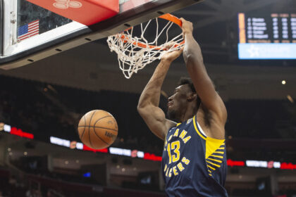 Basketball player in blue and yellow jersey dunks the ball through the hoop during a game at the arena.