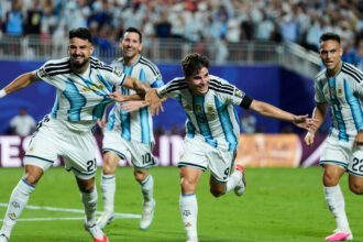 Argentina men’s soccer players celebrate running on the field during a match, blue-and-white striped jerseys and cheering crowd in the background