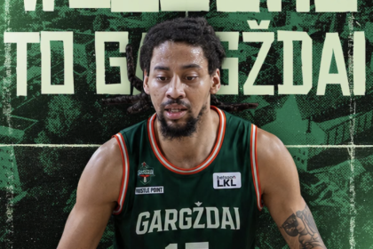 Basketball player in a green Gargždai jersey in front of a green mural reading 'WELCOME TO GARGŽDAI'.