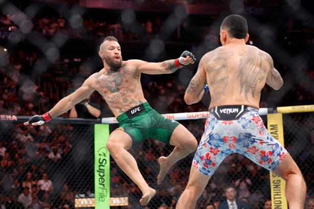 Two male UFC fighters collide in the octagon as the left fighter throws a punch toward his tattooed opponent amidst a crowded arena.