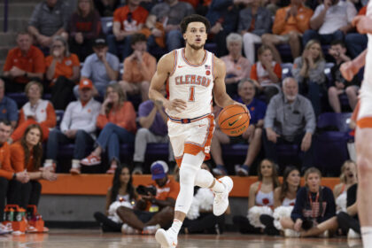 Clemson basketball player (number 1) dribbling down the court with a crowded arena in orange jerseys behind him.